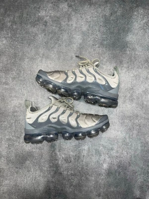 Nike VaporMax Plus - Nike Air VaporMax Plus i grå/silver. Storlek 42,5.  Mycket bra skick överlag. Finns en liten slitning på högerskon vid stortån (sista bilden)