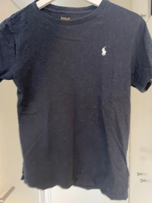 Mörkblå t-shirt från Polo Ralph Lauren - Säljer en mörkblå t-shirt från Polo lauren. Tröjan är knappt använd. Storlek: 10-12/150 cm