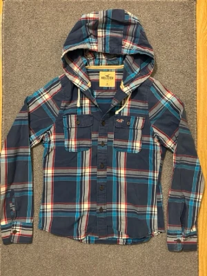 Rutig Hollister Hoodie-Skjorta - Säljer denna mycket trevliga hoodie skjortan från hollister | Mycket bra skick | Storlek S | Längd ≈ 70cm, bredd armhåla-armhåla ≈ 54cm Modell 175cm, 68kg | Hör av vid funderingar! PRIS KAN DISKUTERAS!