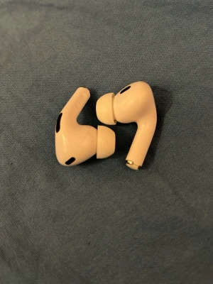 Apple AirPods Pro vita in-ear - Säljer ett par vita Apple AirPods Pro in-ear hörlurar med silikonproppar utan laddningsetui. De har en stilren och kompakt design med svarta detaljer och är tillverkade i plast. Perfekta för dig som vill ha trådlös frihet och grymt ljud.