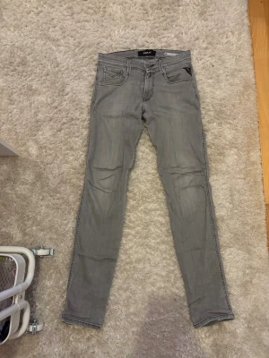 Gråa slim fit jeans från replay - Säljer ett par gråa slim fit jeans från Replay. Jeansen har klassisk femficksdesign, svarta detaljer vid fickorna och raka ben. Perfekta för dig som gillar en clean och stilren look med street-vibe. Pris kan diskuteras