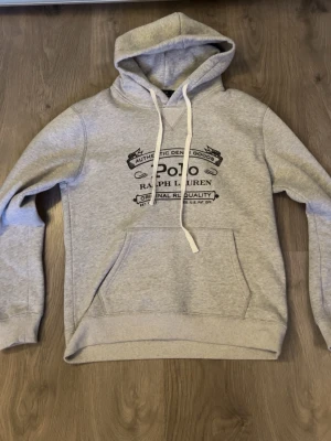 Grå hoodie Ralph Lauren - Grå hoodie från Polo Ralph Lauren. Passar stroken M och har bara används 2 ggr. Den har ett litet streck över texten på bild 3. 
