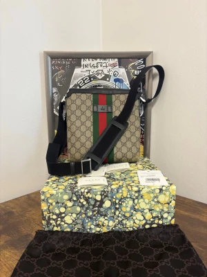 Gucci GG Supreme axelväska - Gucci Crossbody / Axelväska – Mycket fint skick  Säljer en stilren Gucci crossbody-väska i klassiskt GG-monogram med grön/röd webbdetalj. Väskan är sparsamt använd och i mycket bra skick.  ✔ Original Gucci ✔ Justerbar axelrem ✔ Dragkedja ✔ Klassisk och tidlös modell ✔ Perfekt för vardag eller resa  Medföljer: dustbag, box och tags (se bilder). Nypris ca: 8 000–9 000 kr  💰 Pris: 6500kr 📍 Plats: Helsingborg  📦 Kan skickas – köpare står för frakt 💬 Seriösa köpare only