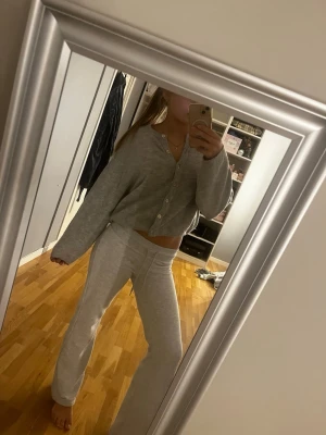 Grå stickad kofta från Gina Tricot - Mysig grå stickad kofta från Gina Tricot i storlek XS. Koftan har lång ärm, ribbade muddar och snygga pärlemorknappar framtil. Enkel, klassisk design som funkar till allt.