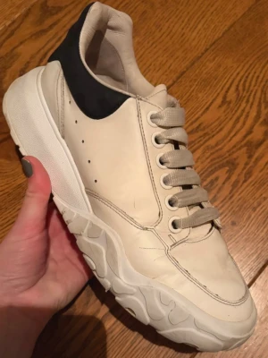 Alexander McQueen dam sneakers - Alexander McQueen Oversized Sneaker – White/Black (dam) i storlek 38  Säljer ett par äkta Alexander McQueen Oversized sneakers i klassisk vit med svart hälkappa.  Skorna är använda och har: Veck i lädret framtill Något Slitage/smuts på sulan (se bilder), detta går självklart att putsa upp, samma med skosnören kan tvättas! I övrigt hela och funktionella Inga hål eller sprickor. Pris satt efter skick. Nypris ca 6800kr