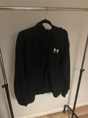 Svart vindjacka från Under Armour - Hej säljer en relativt ny under aormour vindjacka slt xl använd ca 7 ggr säljer pga att jag inte använder den mer och ska rensa min garderob köpt för 900 på boztlet kvitto finns fler bilder kan skickas om de önskas  