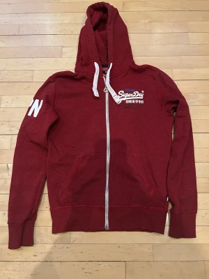Vinröd hoodie från Superdry - Säljer en vinröd hoodie från Superdry med dragkedja. Hoodien är i storlek S. Va inte rädd för att ställa frågor!!