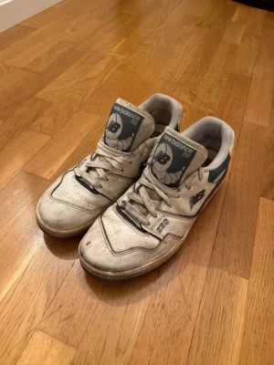 New Balance 550 vita sneakers - Säljer ett par klassiska New Balance 550 sneakers i vitt med grå och mörkgröna detaljer. Skorna har tydlig snörning och en robust sula med New Balance-logga på sidan och tungan. Perfekta för dig som gillar retrostil och streetwear, priset går att diskutera💴