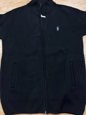 Svart ziptröja från Polo Ralph Lauren - svart ziptröja från polo ralph lauren med två fickor. Tröjan är ny och använd lite  10/10 skick inga problem med den  Storlek L men passar för M också. 