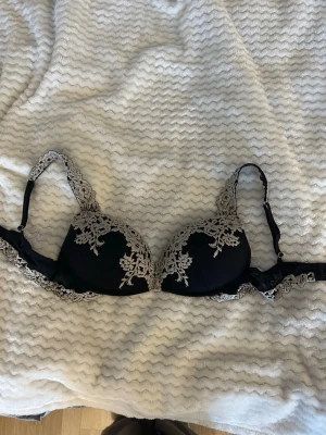 Svart push-up bh med spetsdetaljer - Snygg svart push-up bh med spetsdetaljer längs kupor och axelband. Bh:n har vadderade kupor och justerbara axelband. Vet tyvärr inte storlek då jag har klippt bort lappen❣️