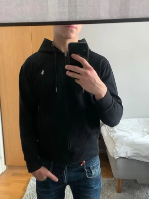 Raulph Lauren zip - Säljer en svart zip hoodie från Ralph Lauren. Det är i bra skick och utan några fel/hål. Storlek S. Modellen är 182cm och ca 72kg.