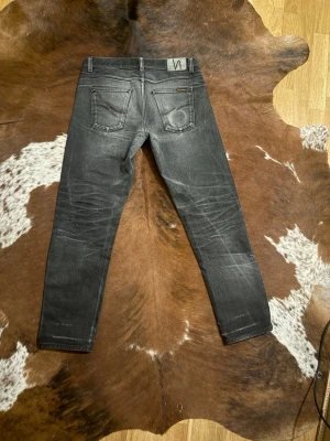 Selvage nudie GrittyJackson black - Tjena! Säljer dess otroligt snygga svarta selvage jeans, modellen är GrittyJackson och sitter straight, mätt finns på sista bilderna, finns lite skavanker vilket är förväntat på jeans med denna tvätt, W33/L32, hör av dig vid funderingar!🙌