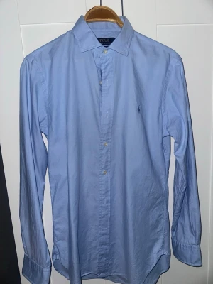 Ljusblå skjorta Polo Ralph Lauren - Klassisk ljusblå skjorta från Polo Ralph Lauren i slim fit-modell. Använd en gång, säljer eftersom den inte passar mig längre. Hör av dig vid frågor!