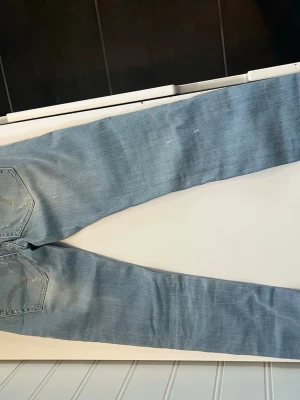 Ljusblå slitna skinny dondup jeans - Säljer ett par ljusblå skinny jeans med slitningar och distressed detaljer på framsidan. Jeansen har klassiska bakfickor och är tillverkade i mjukt denimtyg med stretch. Perfekta för en avslappnad och trendig look.