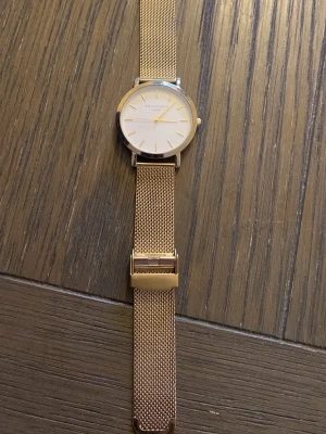 Roséguld klocka från Rosefield - Stilren klocka från Rosefield i roséguld med mesharmband i metall. Urtavlan är vit med minimalistiska markeringar och boetten är rund. Perfekt accessoar för dig som gillar en clean och modern look.