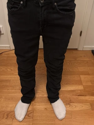 Svarta slim fit jeans - Säljer ett par svarta slim fit jeans med klassisk femficksdesign och normal midja. Jeansen har raka ben och är tillverkade i ett stretchigt material för extra komfort. Perfekta för dig som gillar en enkel och stilren look.