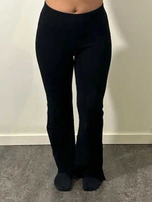 Svarta utsvängda leggings - Säljer ett par svarta leggings med utsvängda ben och hög midja. De är stretchiga och sitter tight upptill för en snygg siluett. Materialet är tjockt, mjukt och följsamt. Nederkanterna är klippta! Jag är 156cm lång 🥰