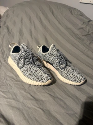 Yeezy Boost 350 Turtle Dove sneakers - Säljer ett par Yeezy Boost 350 Turtle Dove med stickad ovandel i grått och svart mönster, vita tjocka sulor och matchande snören. Ikonisk siluett med låg profil och pull-tab bak. Perfekta för dig som vill sticka ut med en streetwear-klassiker.
