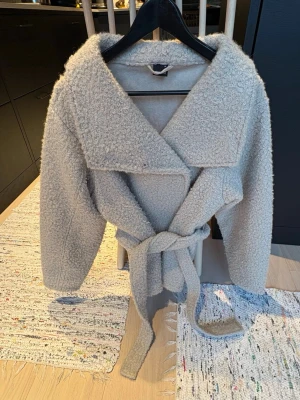 Beige  teddyjacka med knytskärp - Supermjuk och fluffig teddyjacka i ljusgrått/beige med bred krage och knytskärp i midjan. Perfekt till våren 💗