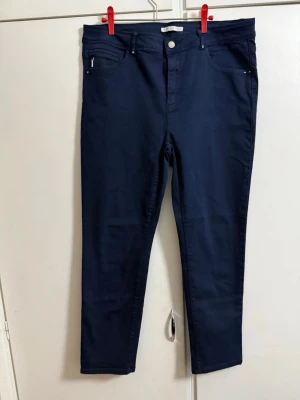 Mörkblå jeans med hög midja från Armand Thiery - Snygga mörkblå skinny jeans med hög midja och klassisk femficksdesign. Jeansen har smala ben och silverfärgade nitar vid fickorna. Perfekta till en avslappnad eller trendig look. Materialet känns stretchigt och bekvämt.