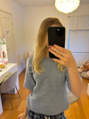 Ljusblå stickad tröja - Mysig ljusblå stickad tröja med rund halsringning och korta ärmar.🩵 Tröjan har en avslappnad passform och ribbade kanter vid hals, ärmslut och nederkant. Perfekt för dig som vill ha en enkel men snygg look som är enkel att styla. Stor i storleken och passar mig som är 14 år!😍🌸💓✨