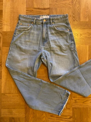 Ljusblå raka jeans från Bershka - Ljusblå jeans från Bershka med klassisk femficksdesign och raka ben. Jeansen har gylf med dragkedja och knapp, samt detaljer i kopparfärgad metall. Tillverkade i bomullsdenim med en avslappnad passform.