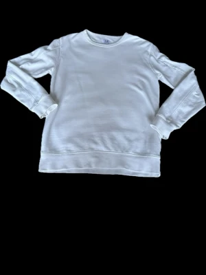 Vit sweatshirt från C.P. Company - Vit sweatshirt från C.P. Company med rund halsringning och ribbade muddar. Enkel och stilren design utan tryck eller detaljer. Perfekt för en clean och avslappnad look. Oanvänd då den är för stor. Nypris 2000kr