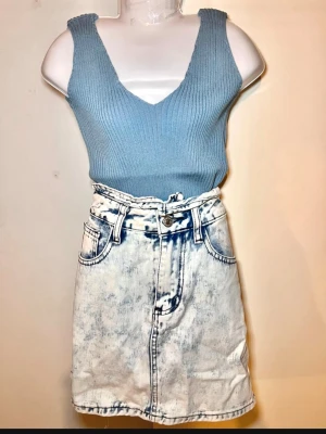 Set 2st Blå ribbad ärmlös linnetopp och jeans kjol  - Snygg blå ribbad linnetopp med v-ringning och breda axelband. Toppen är croppad och har en tight passform som framhäver figuren. Perfekt att matcha med jeans eller kjol för en trendig look.