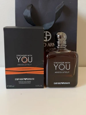 Emporio Armani Stronger With You - Emporio Armani Stronger With You Absolutely är en parfym för honom med en elegant, mörkbrun glasflaska och silverfärgad kork. Flaskan har en stilren, fyrkantig form och kommer i en svart kartong med orange detaljer. Doften är intensiv och modern.