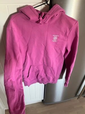 Rosa hoodie från hm - Snygg rosa hoodie från hm med vit logga och text på bröstet och ryggen. Perfekt för en avslappnad och trendig stil. Frånnherrqvdwlning men passar även tjejer 💞