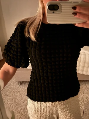 Svart puffärm topp med struktur - Säljer en svart topp med coolt rutigt strukturmönster och puffiga korta ärmar.🖤