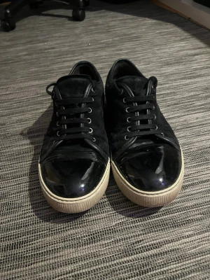 Svarta sneakers med lackad tå - Svarta sneakers med cool mix av mocka och blankt lack på tån. Klassisk vit sula och svarta skosnören. Perfekta för dig som gillar stilrena men ändå unika skor. Passar till det mesta och ger en clean vibe.