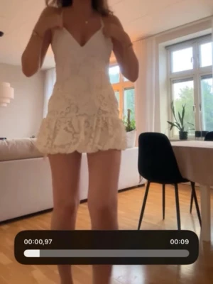 Vit spetsklänning med volang - Söt kort vit klänning med spets och volang nertill. Klänningen har smala axelband, v-ringning och figurnära passform upptill. Perfekt för sommarens tillfällen och har ett romantiskt uttryck med sitt blommiga spetsmönster.