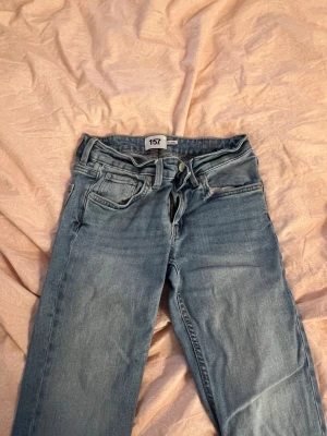 Ljusblå jeans från 157, storlek XS - Säljer ett par ljusblå jeans från 157 i storlek XS med full längd. Klassisk femficksmodell med dragkedja och knapp framtill. Perfekta för dig som gillar en avslappnad och stilren look till vardags. Krympt ca 3 cm i tvätten