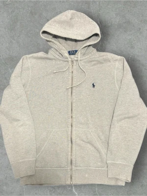 Polo Ralph Lauren Zip Hoodie Grå - 📍Storlek:M  💪🏽Skick:Ny utan prislapp   📐Mått:Längd:64cm:Bred:47:cm:  📎Material:86”%Bomull:Polyester14%  📦Skickar alltid inom 24h  💸Köp fler plagg för att få billigare pris  ✅Äkthetsgaranti