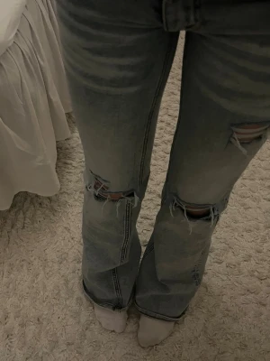 Ljusblå Cheep Monday jeans med slitningar - Säljer ett par såå snygga ljusblå bootcut Cheap Monday jeans från Weekday som tyvärr nu är för små. Jeansen har slitningar och hål på båda benen som jag gjort själv därav priset. De är lite slitna längst ner men på ett snyggt sätt! Storlek 24/30.