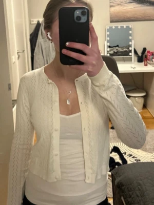 Vit kofta med diskret mönster - Säljer en supersöt vit kofta med diskret stickat mönster och knappar framtill. Koftan har lång ärm och är lite kortare i modellen, perfekt att ha över ett linne eller t-shirt. Materialet är mjukt och tunt, vilket gör den enkel att styla. Storlek 146/152 men passar perfekt på mig som är 160 lång så skulle säga att den är lite stor i storleken.