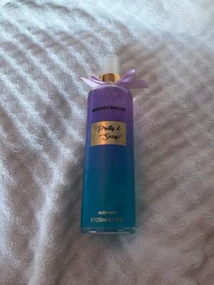 Pretty & Sexy Body Mist 250ml - Pretty & Sexy Body Mist från Women'secret i en snygg flaska med lila och blå toning, gulddetaljer och en söt rosett vid sprayhuvudet. Flaskan rymmer 250 ml och har en modern, feminin design som passar perfekt på sminkbordet. SE SIST BILDEN FÖR ATT SE HUR MYCKET SOM ÄR KVAR! MYCKET MER ÄN HÄLFTEN! ÄVEN EN SKAD PÅ SJÄLVA TEXTEN PÅ PARFYMEN FRAM!💓🌸