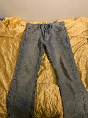 Ljusblå raka jeans från 157 - Säljer ett par klassiska ljusblå jeans från 157 med rak passform och fem fickor. Jeansen har gylf med knapp och dragkedja samt tydliga kontrastsömmar. Perfekta för en avslappnad och tidlös look.