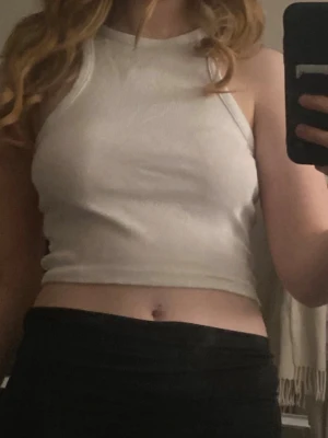 Vit croppad ribbad linnetopp - Säljer en vit croppad linnetopp med ribbad struktur och hög hals. Toppen är ärmlös och har en enkel, clean look som passar perfekt till både jeans och kjol. Materialet känns mjukt och stretchigt, vilket gör den bekväm att bära hela dagen. Den är köpt väldigt länge sedan (färgen börjar bli lite beige grå, om man kollar noga)