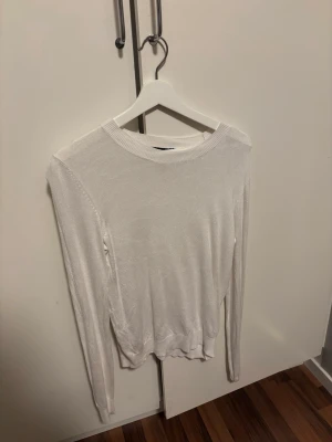 Vit tunn stickad tröja  - Säljer en vit tunn stickad tröja från lager157 med rund halsringning och långa ärmar. Tröjan har en enkel och stilren design med ribbade muddar vid hals, ärmslut och nederkant. Perfekt att matcha med jeans eller kjol. Aldrig använd. Storlek S