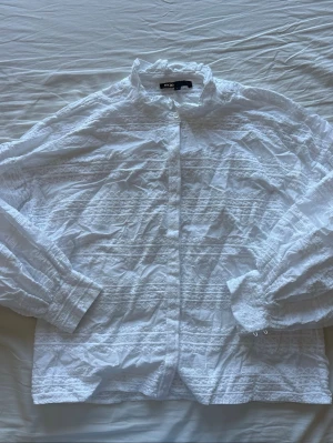 Vit skjorta med broderade detaljer - Säljer en vit skjorta från maje med broderade mönster och knappar framtill. Skjortan har långärmade puffärmar och en klassisk krage. Perfekt för dig som gillar en romantisk och stilren look.