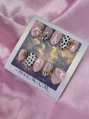 Bijou (S);Short Almond - Unika handgjorda press-on naglar i kort-mandelform. Mix av ljusrosa, nude och vita naglar med svarta prickar, guldiga kedjedetaljer och vita prickar. Handgjorda i S: 15 mm, 11,5 mm, 12 mm, 11 mm, 9 mm, och designade för att sticka ut med trendiga mönster och detaljer.