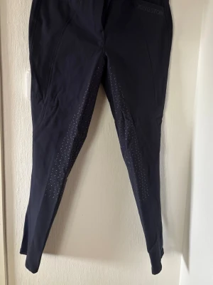 Svarta ridbyxor från Kingston - Säljer ett par marinblåa ridbyxor från Kingston med silikonmönster längs insidan av benen för extra grepp. Byxorna har en smal passform och är tillverkade i ett stretchigt funktionsmaterial som passar perfekt för träning och ridning.