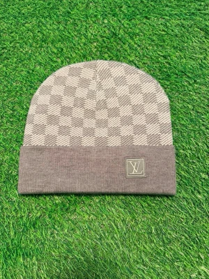 Grå Louis Vuitton mössa med rutmönster - Säljer en snygg grå mössa från Louis Vuitton med klassiskt rutmönster och vikt kant. Mössan har en diskret LV-logga framtill och är stickad i mjukt material som känns lyxigt. Perfekt accessoar för att höja din outfit.