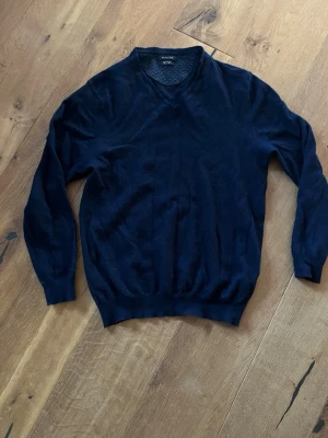 Massimo dutti tröja - Snygg mörkblå v-ringad tröja Massimo dutta. Tröjan har långa ärmar och ribbade muddar vid ärmslut och nederkant. Perfekt att bära över en skjorta eller t-shirt. Materialet är mjukt och tunt, vilket gör den bekväm att ha på sig.