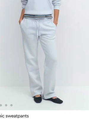 Ljusgråa raka mjukisbyxor - Säljer ett par ljusgrå mjukisbyxor med raka ben och dragsko i midjan. Byxorna har en avslappnad passform och resår i midjan för extra komfort. Perfekta för chill dagar eller när du vill vara bekväm men ändå se snygg ut.