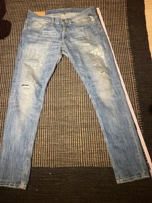 Dondup George  - Snygga ljusblå jeans med slitningar och patchdetaljer på höger lår. Klassisk femficksmodell med smal passform och dragkedjegylf. Perfekta för en avslappnad streetstil. W34 passar 33