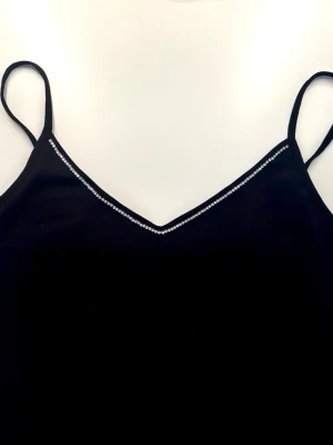 Svart linne med diamanter  - Svart linne med diamanter runt urringningen (går även att köpa med pärlor runt urringningen). Perfekt nu till sommaren. Enkel och stilren design som passar till många outfits. Finns i alla storlekar (Tvätta helst i 30 grader)