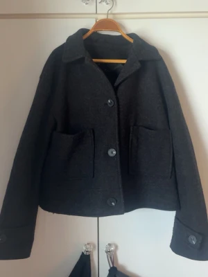 Svart kappa - säljer en mörkgrå/svart kappa från lager 157 i storlek S. Kappan har klassisk krage, tre knappar och helfodrad insida. Perfekt för fika vår dagar och enkel att matcha med olika outfits!❤️